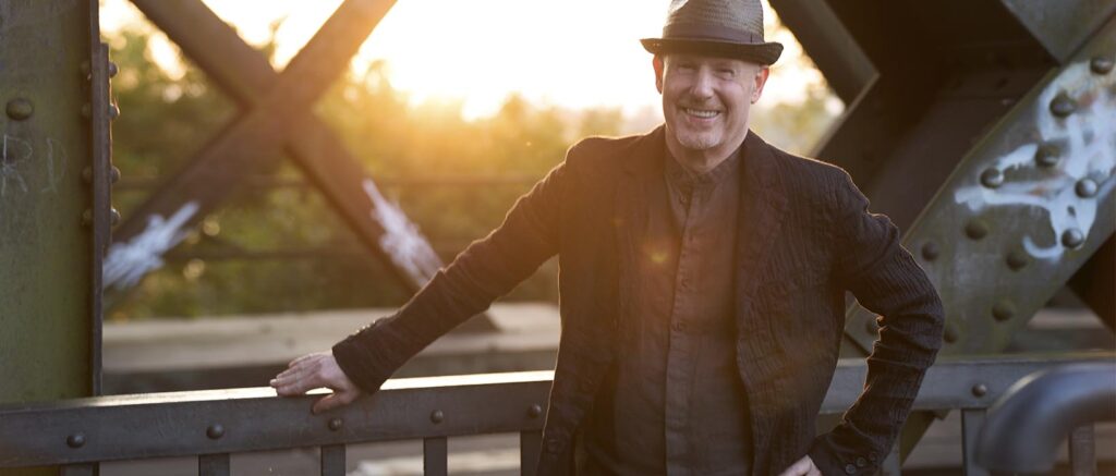 Authentic Personal Shooting: Mann mit Hut im Gegenlicht auf einer Eisenbahnbrücke