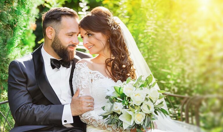 Brautpaar sitzt lächelnd auf einer Parkbank im Weinheimer Hermannshofs