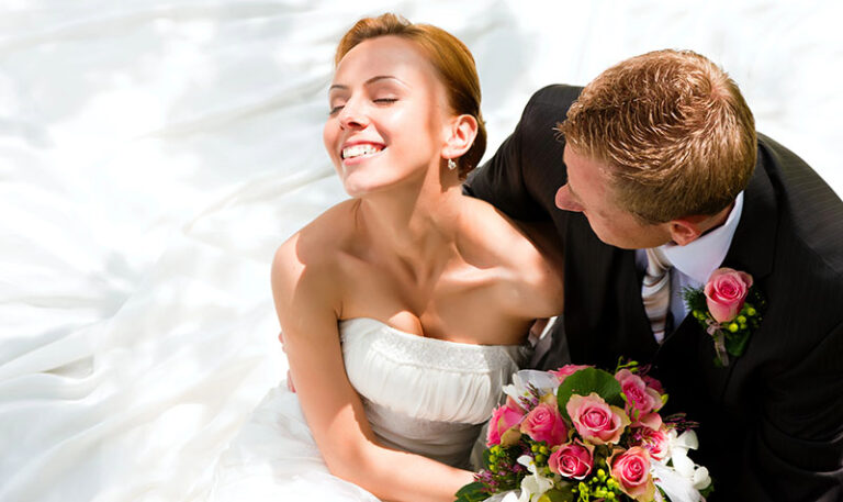 Brautpaar mit Rosenbukett von oben fotografiert mit lächelnder Braut