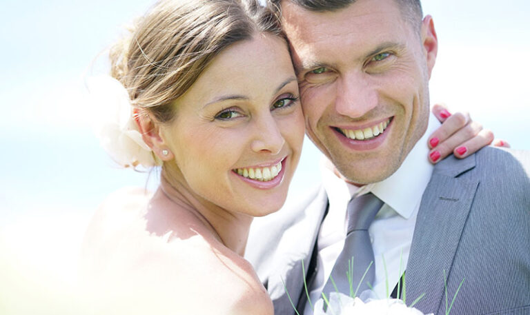Nahaufnahme: Strahlend lächelndes Brautpaar im Gegenlicht