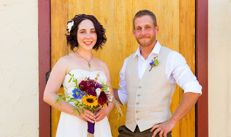 bäuerliches Brautpaar mit rustikalem Brautstrauß vor Tür