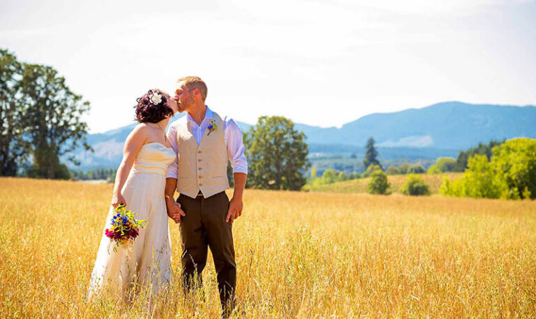 Sich küssendes Brautpaar in mitten eines goldgelben Weizenfeldes