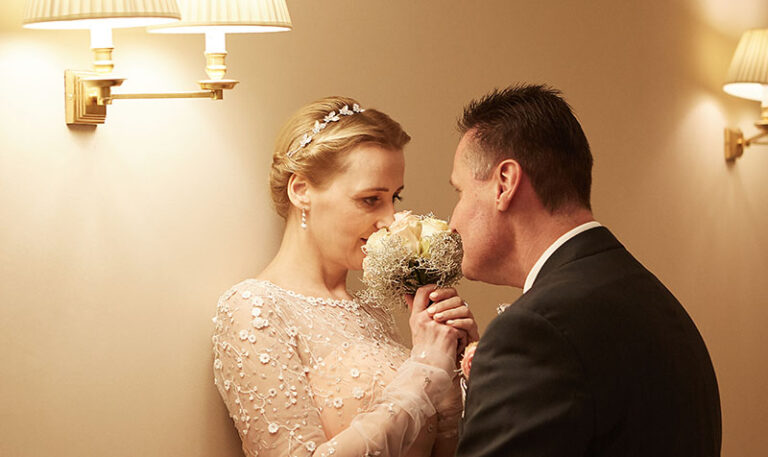 Hotelhochzeit im Rheinland: Brautpaar riecht verträumt am Hochzeitsstrauß