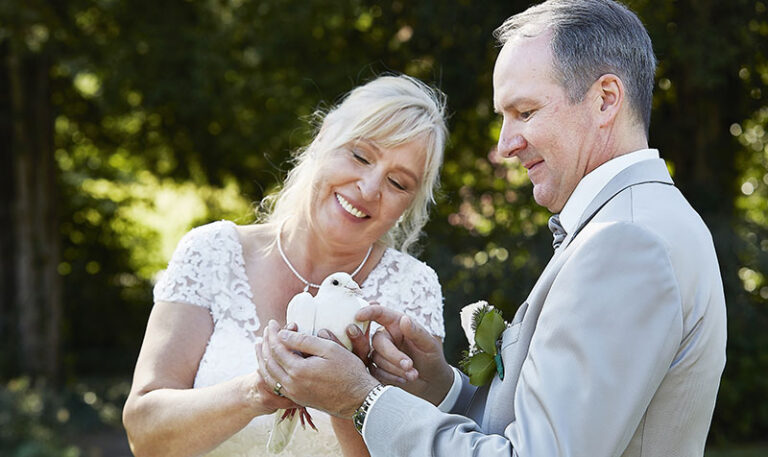 Älteres Brautpaar streichelt eine weiße Taube