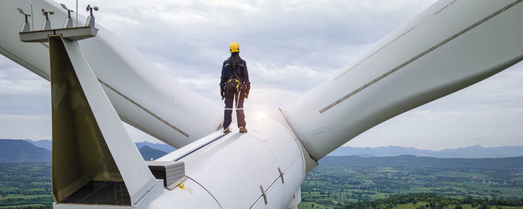 Drohnenaufnahme eines Prüfingenieurs auf der Turbine eines Windrads 130 Meter über dem Boden