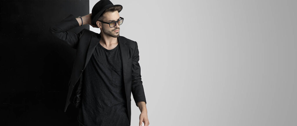 Portrait Junger Mann mit Hut vor schwarz-weißen Hintergrund